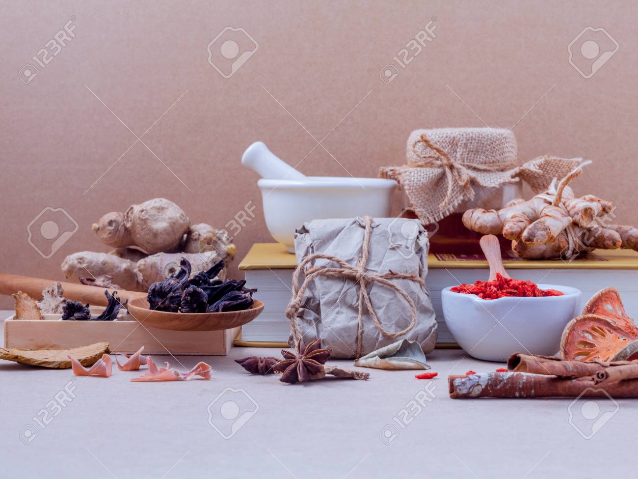 Alternative healthcare dried various Chinese herbs in wooden box and dried roselle in wooden spoon on medical textbook with mortar on brown background. - 51659570 Alternative healthcare dried various Chinese herbs in wooden box and dried roselle in wooden spoon on medical textbook with mortar on brown background. - 51659570