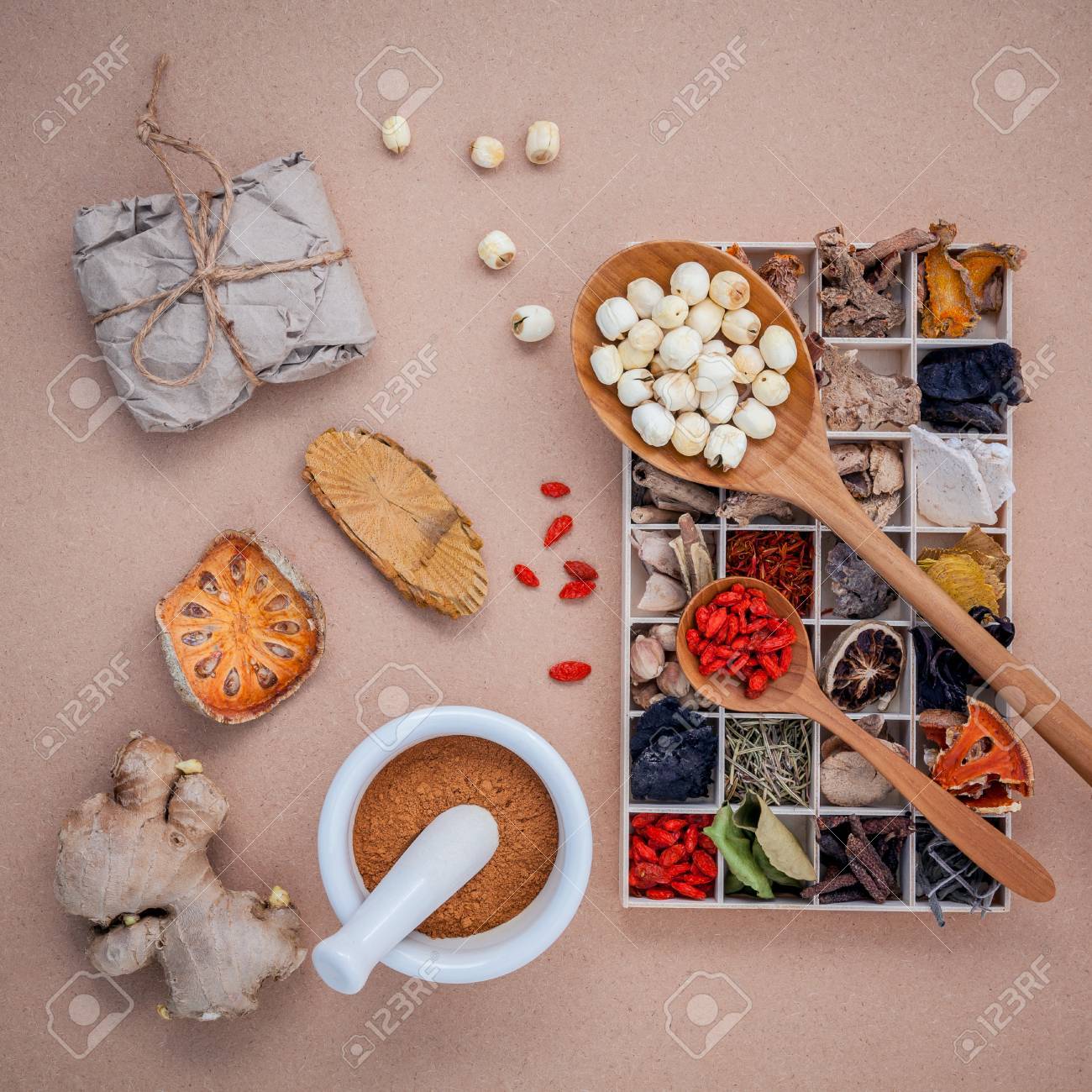 Alternative health care dried various Chinese herbs in wooden box , dried quince ,ginger and lotus seed in wooden spoon with mortar on brown background. - 51662999 Alternative health care dried various Chinese herbs in wooden box , dried quince ,ginger and lotus seed in wooden spoon with mortar on brown background. - 51662999