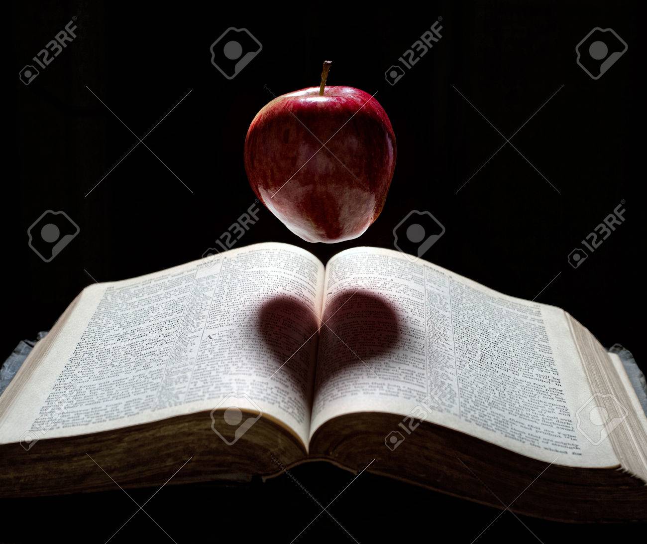 An apple floats above a Bible with a heart shadow. - 27594894 An apple floats above a Bible with a heart shadow. - 27594894