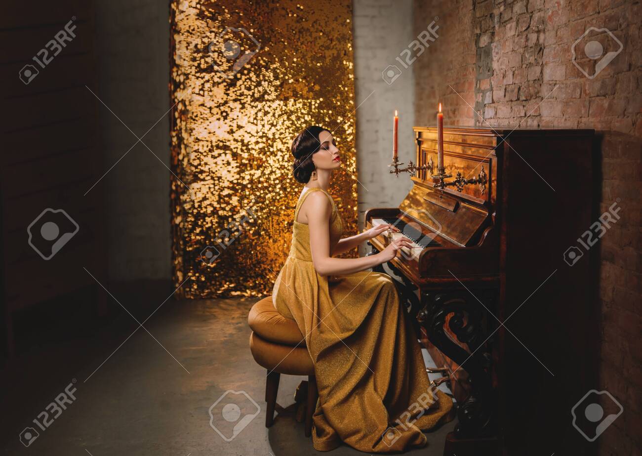 Young woman with finger wave hairstyle gold dress vogue fashion old style 1920 play piano candles romantic burning. Retro Great Gatsby backdrop shine sparkle room brick wall. Musician graduate party - 141943627 Young woman with finger wave hairstyle gold dress vogue fashion old style 1920 play piano candles romantic burning. Retro Great Gatsby backdrop shine sparkle room brick wall. Musician graduate party - 141943627