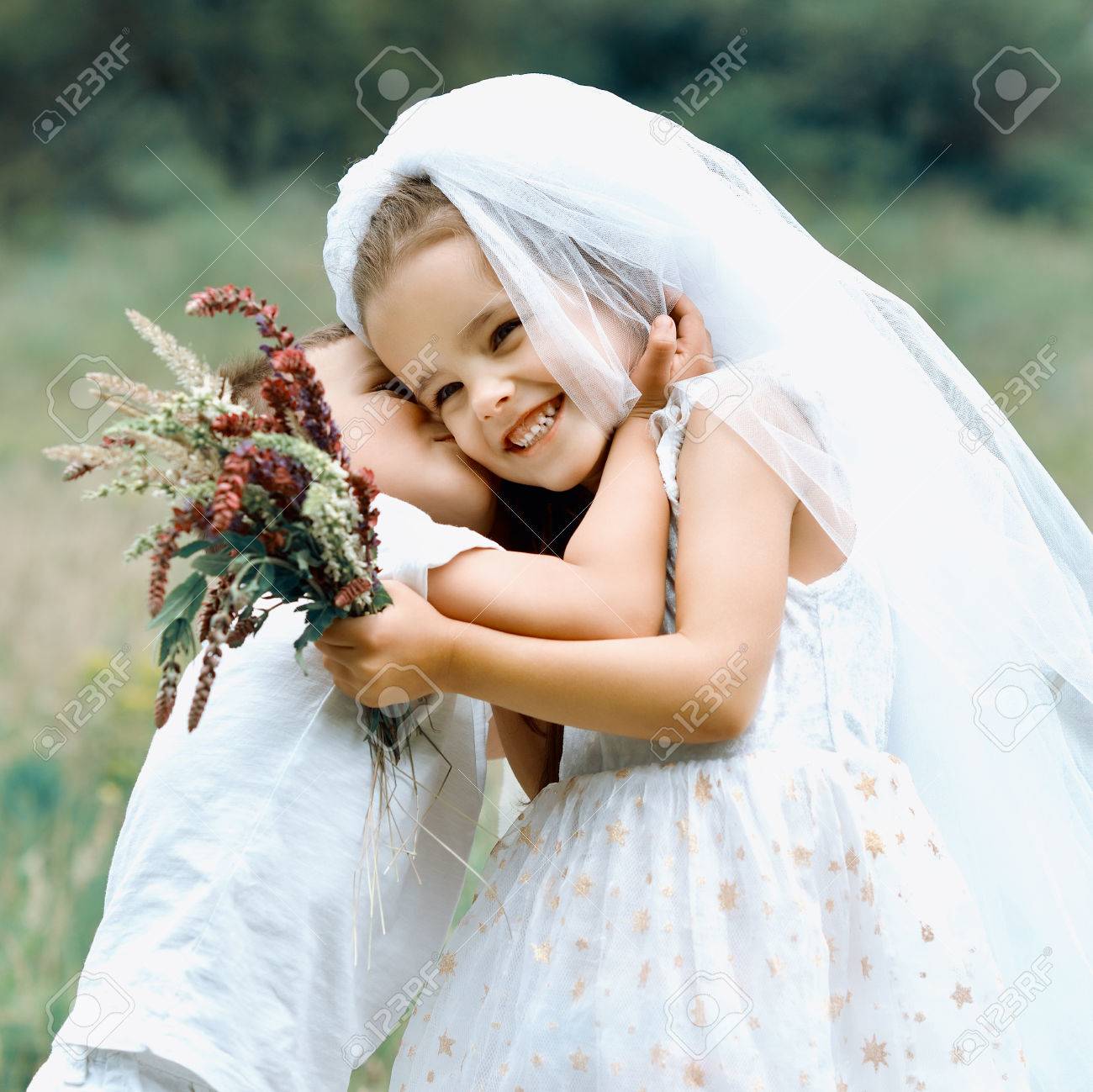 若い新郎新婦結婚式夏の屋外プレイします 子供には 新婚夫婦が好きです 少女花嫁ホワイト ドレスとキス彼女の小さな男の子の新郎新婦の子供のゲーム ブライダル 結婚式のコンセプト の写真素材 画像素材 Image
