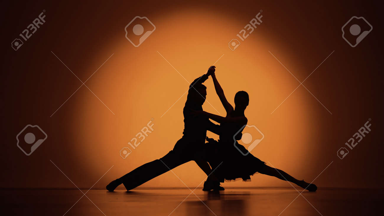 ダンサーのカップルがお互いに近づき、アルゼンチンタンゴを踊り始めます。オレンジ色の茶色の背景にスタジオでラテンの社交ダンスのエレメント。暗いシルエット。スローモーション対応、4fpsで59.94K。の写真素材・画像素材  Image 187255661 社交ダンス、アルゼンチン ..., image size:1300x731