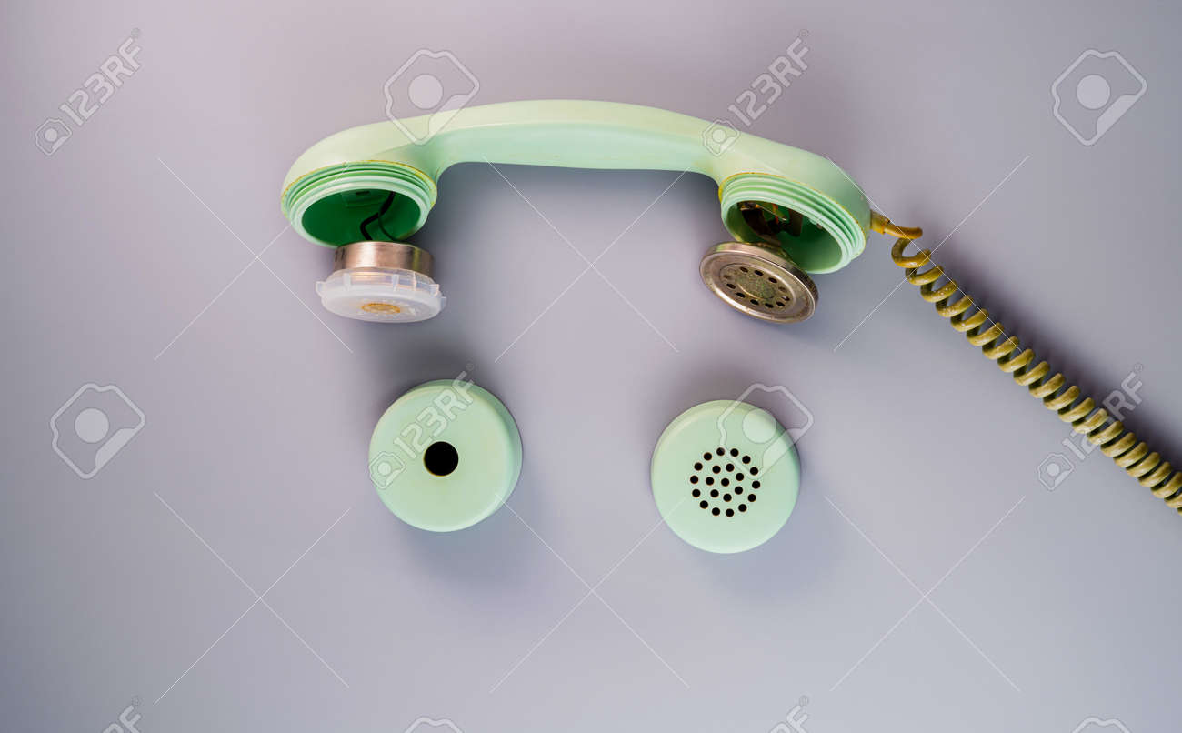 An Old Broken Green Telephone Receiver With Twisted Cord On A Gray  Background. Vintage Untwisted Telephone Receiver. Disassembled Handset From  A Retro Landline Phone. Top View. Фотография, картинки, изображения и  сток-фотография без
