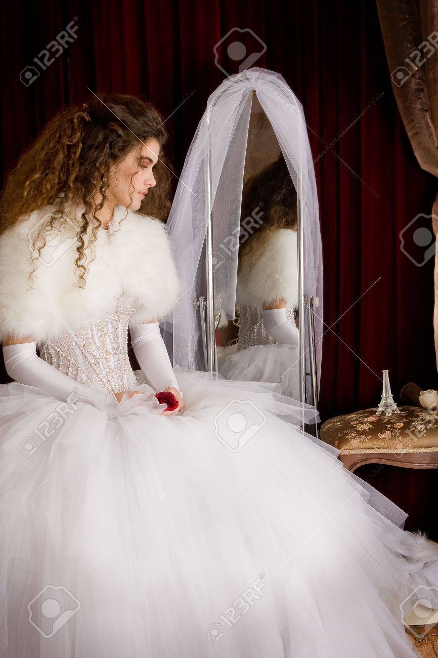 The Bride With Long Brown Curly Hair In A Wedding Dress Sitting