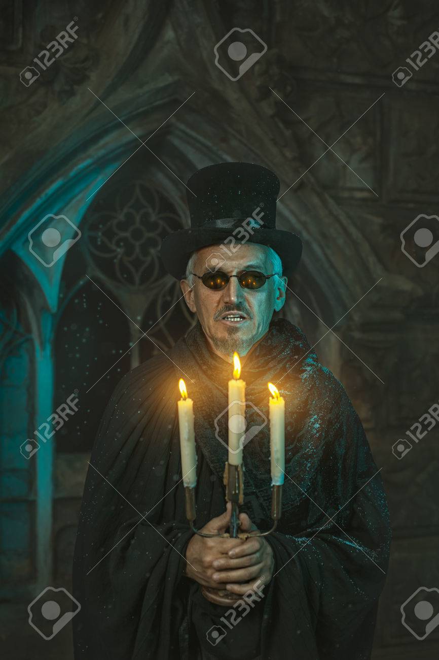 どの蝋燭で手で燭台を持つ邪悪な魔術師男が燃えています の写真素材 画像素材 Image
