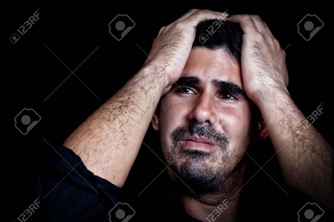 Portrait of a stressed and sad young man with a dramatic expression on a black background - 12748285 Portrait of a stressed and sad young man with a dramatic expression on a black background - 12748285