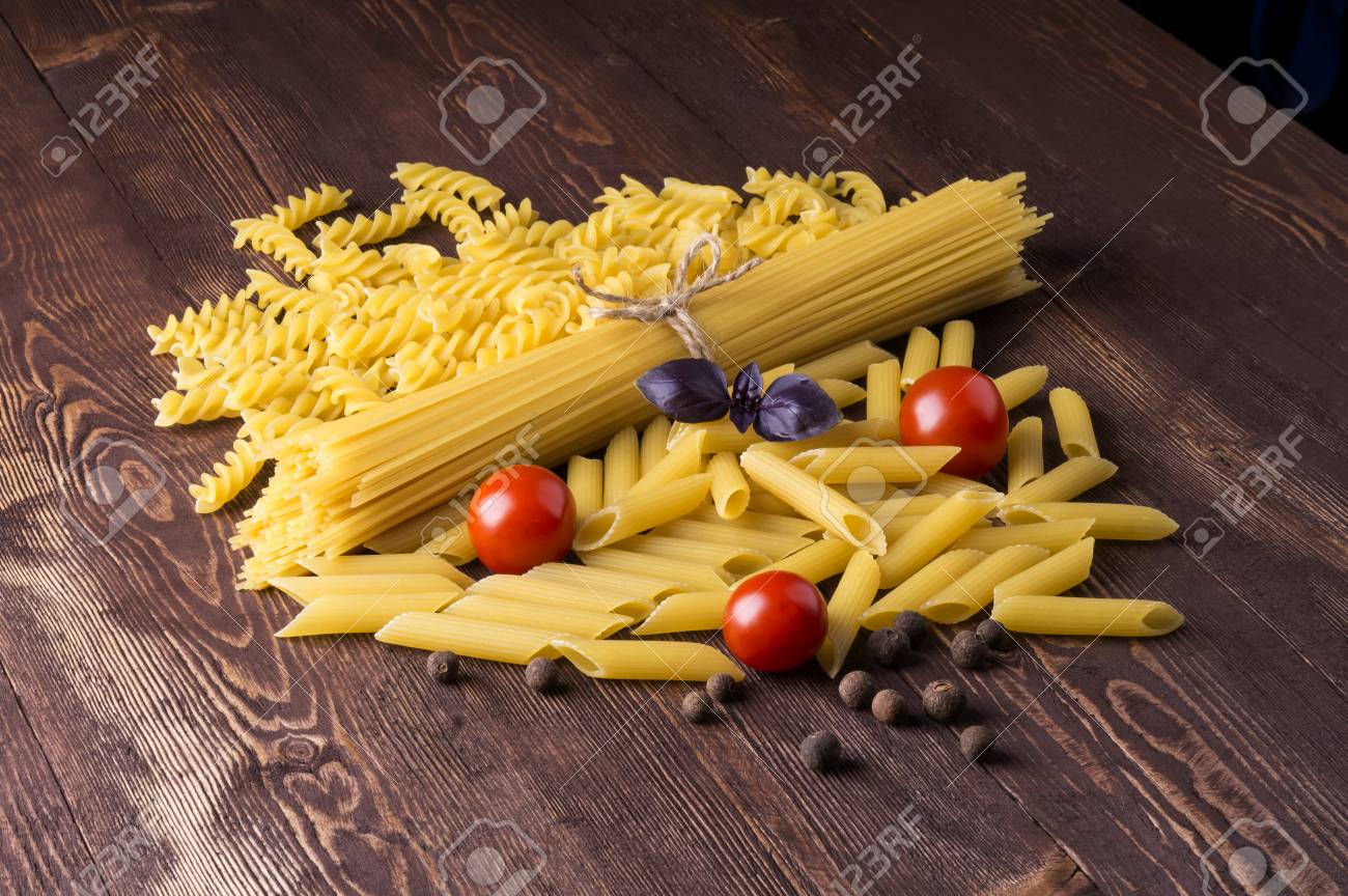 イタリアのパスタの種類パスタ テーブルの上の調理のパスタ 混合乾燥パスタの選択とチェリー トマト バジル 甘いエンドウ豆 の写真素材 画像素材 Image