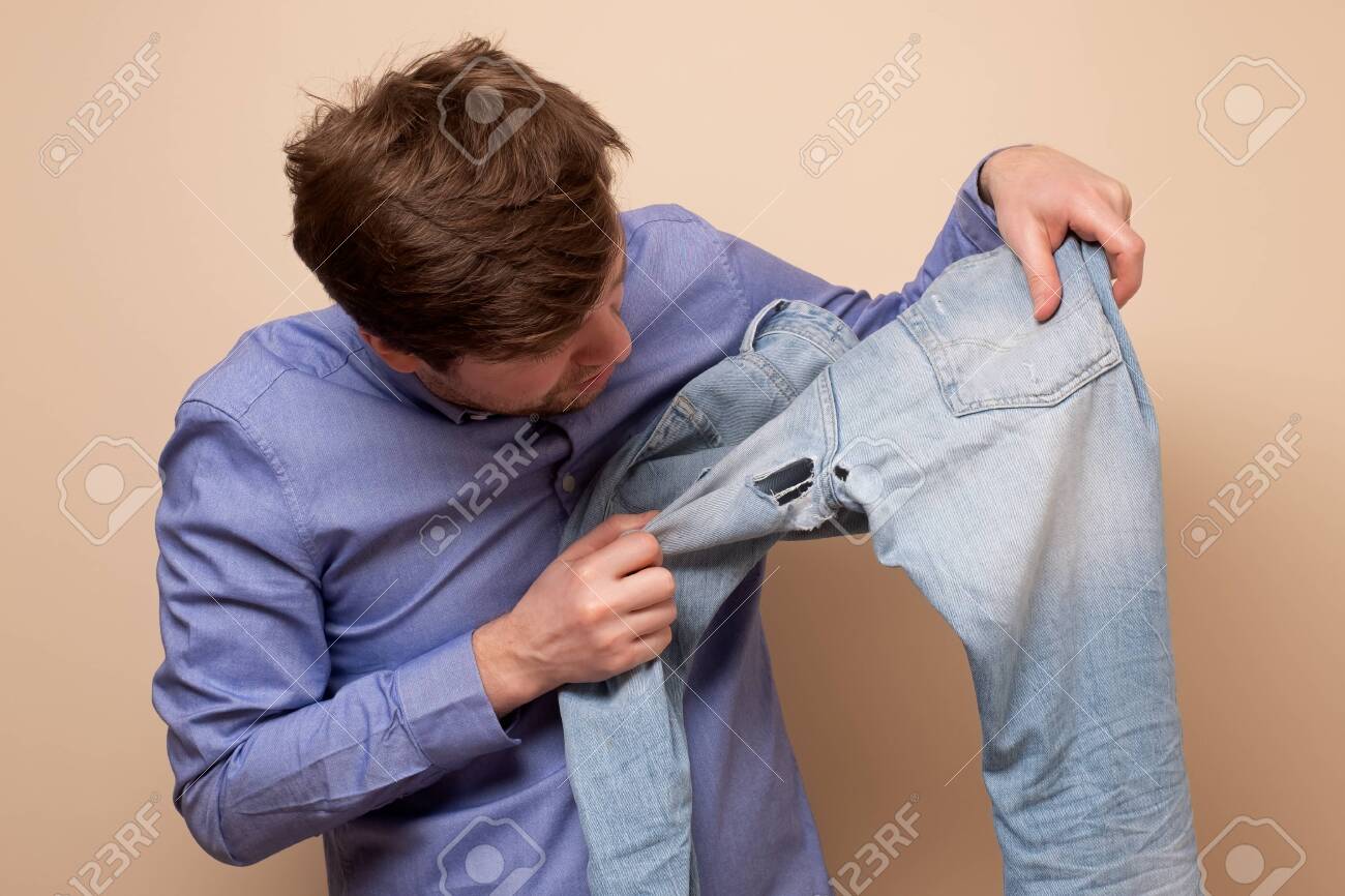 Hole And Threads On Denim Jeans. Sad Caucasian Man Holding Destroyed Blue  Jeans Showing Holes. Stock Photo, Picture and Royalty Free Image. Image  143117220.