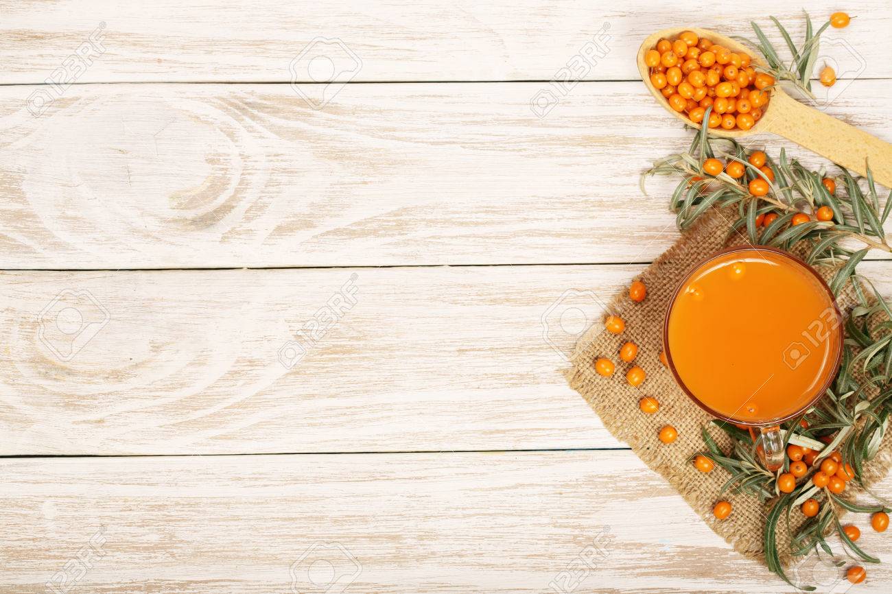 Sea buckthorn juice or tea with berries on a white wooden background with copy space for your text. Top view. - 84503493 Sea buckthorn juice or tea with berries on a white wooden background with copy space for your text. Top view. - 84503493