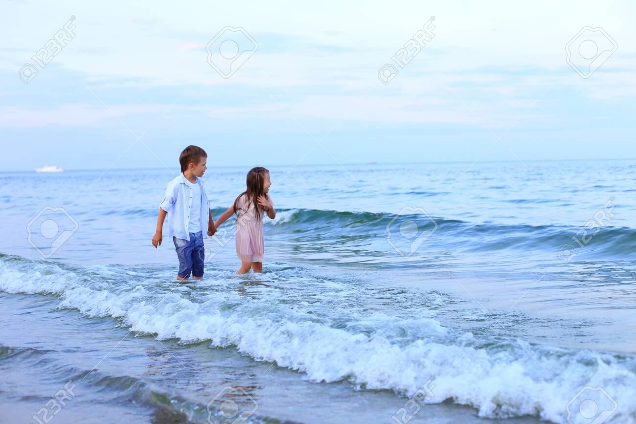 Two children run along the sea near the shore - 150765418 Two children run along the sea near the shore - 150765418