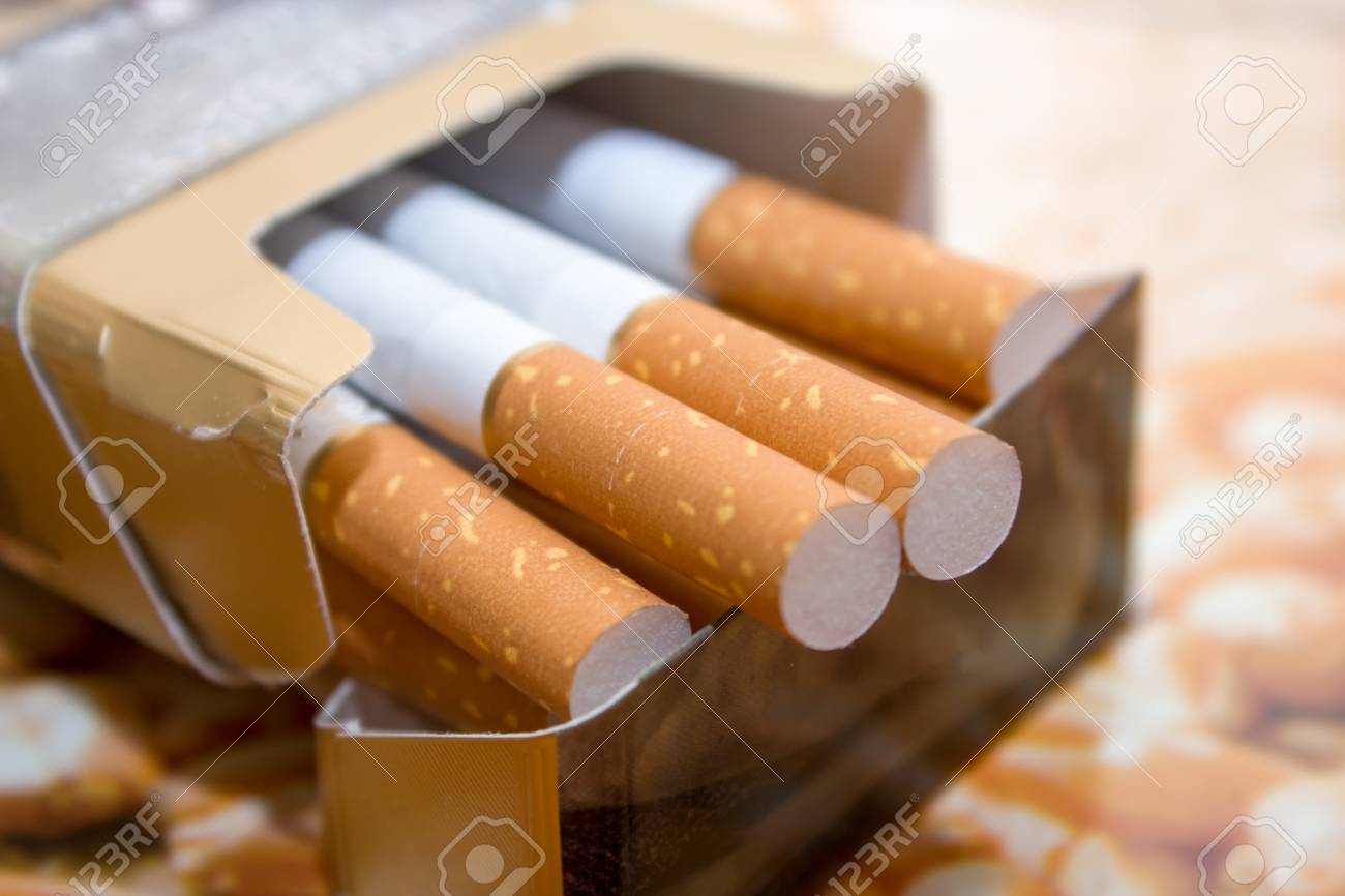 Cigarettes in a pack. Yellow filter. Harm to health. Bad habit. A pack of cigarettes on the table. open pack of cigarettes. - 121867451 Cigarettes in a pack. Yellow filter. Harm to health. Bad habit. A pack of cigarettes on the table. open pack of cigarettes. - 121867451
