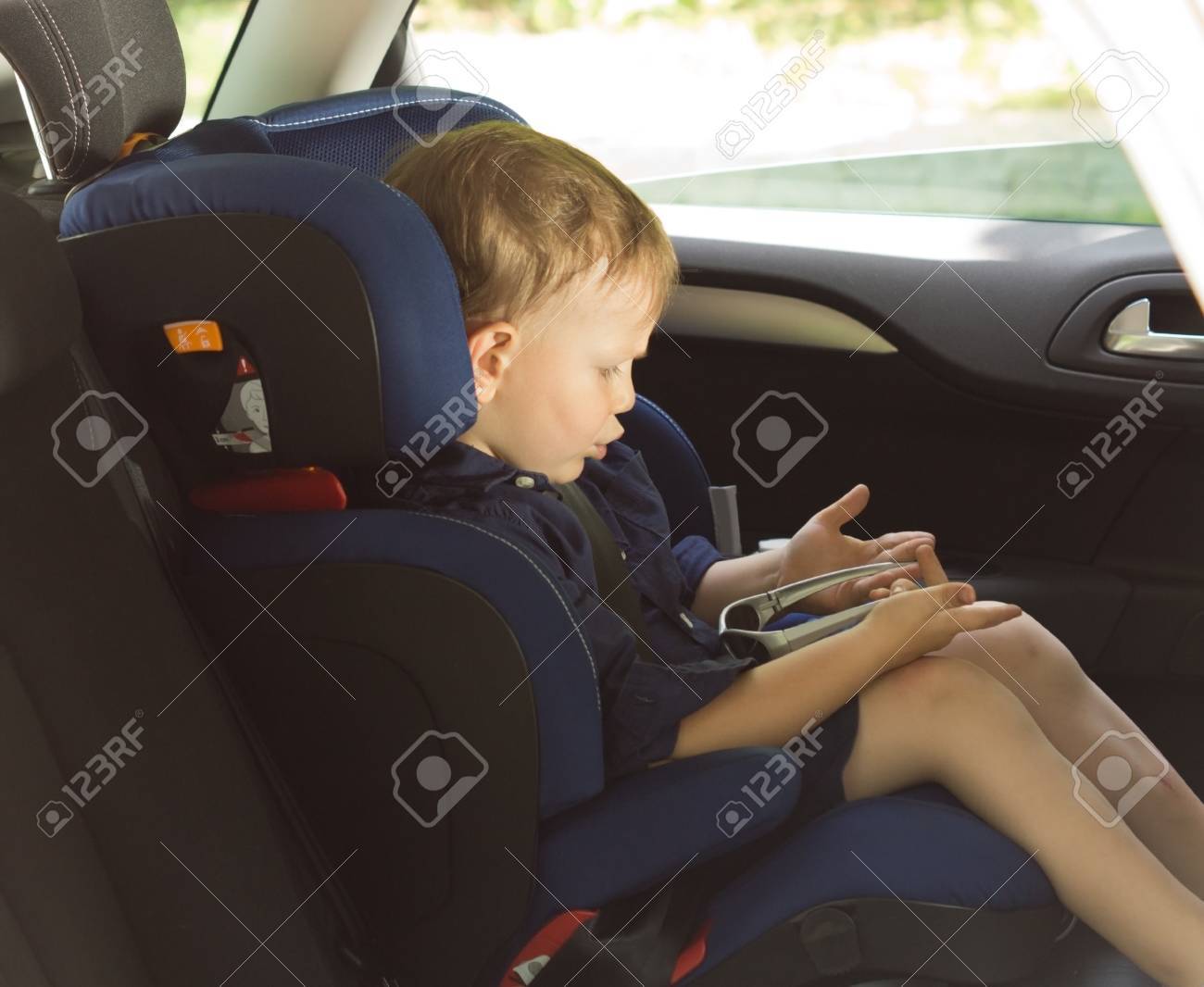自分のゲームを彼の子供の安全に紐で縛らながら車で面白い男の子待っている座席 の写真素材 画像素材 Image