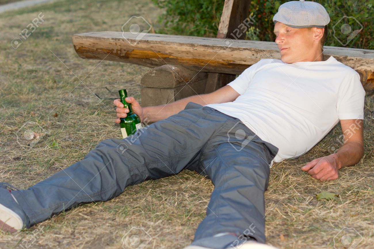 Drunk Man Fallen Down On The Ground With A Bottle In His Hand