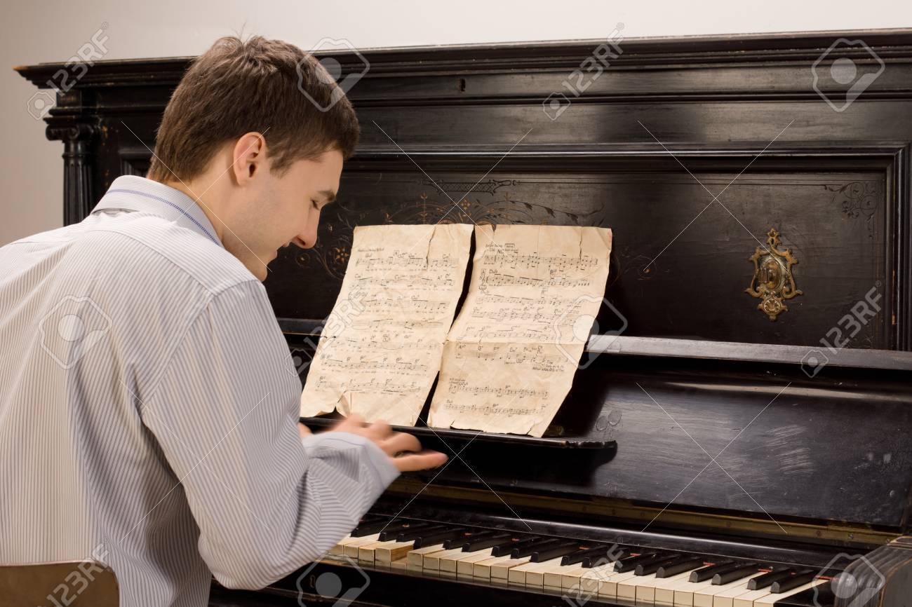 View From The Rear Of A Young Man Smiling As He Plays The Piano Using An Old Vintage Music Score On An Upright Wooden Piano Stock Photo Picture And Royalty Free Image