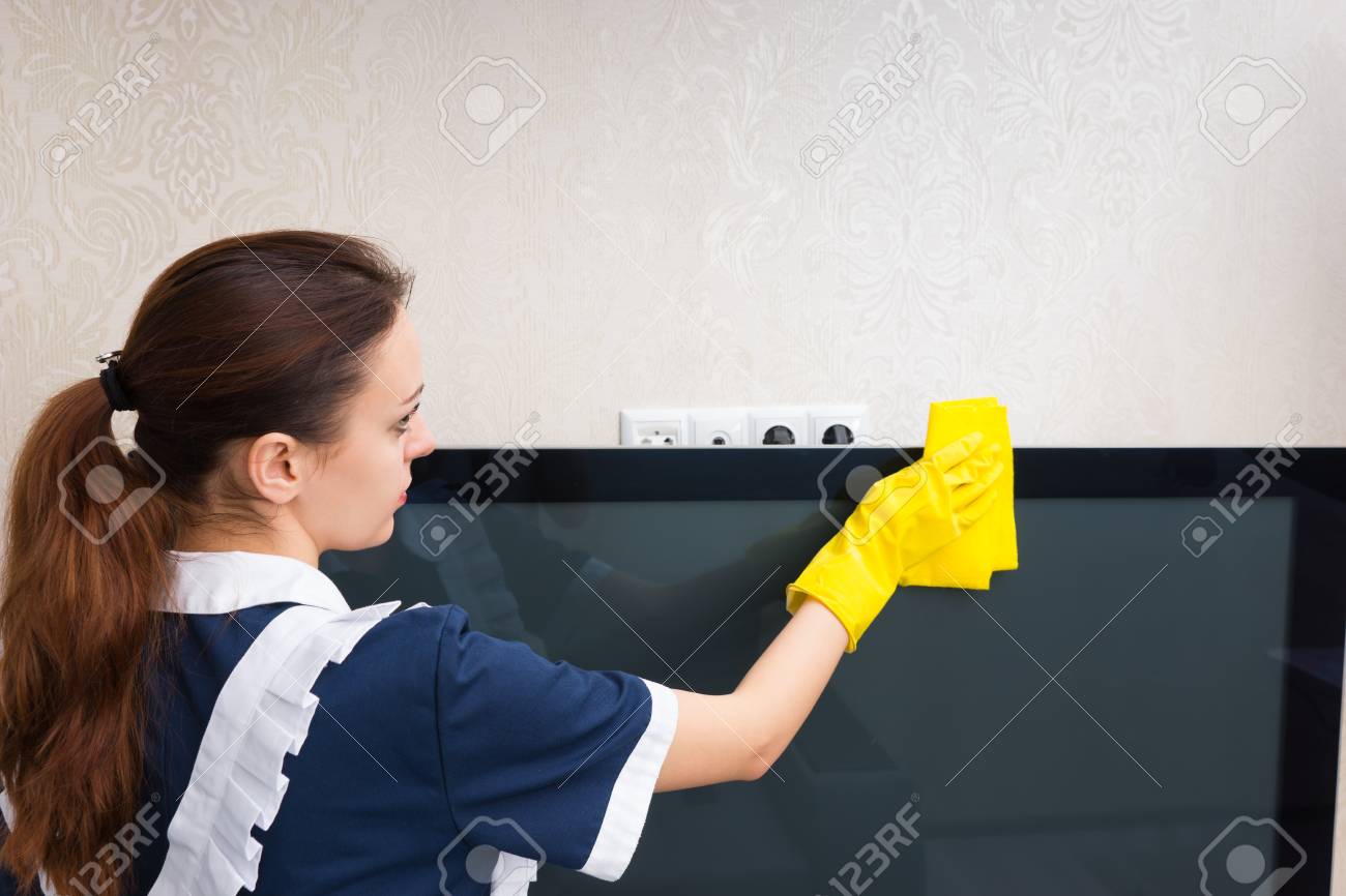 布で テレビを散布ニートの制服と黄色の手袋を着用する若い家政婦をクローズ アップ背面 の写真素材 画像素材 Image