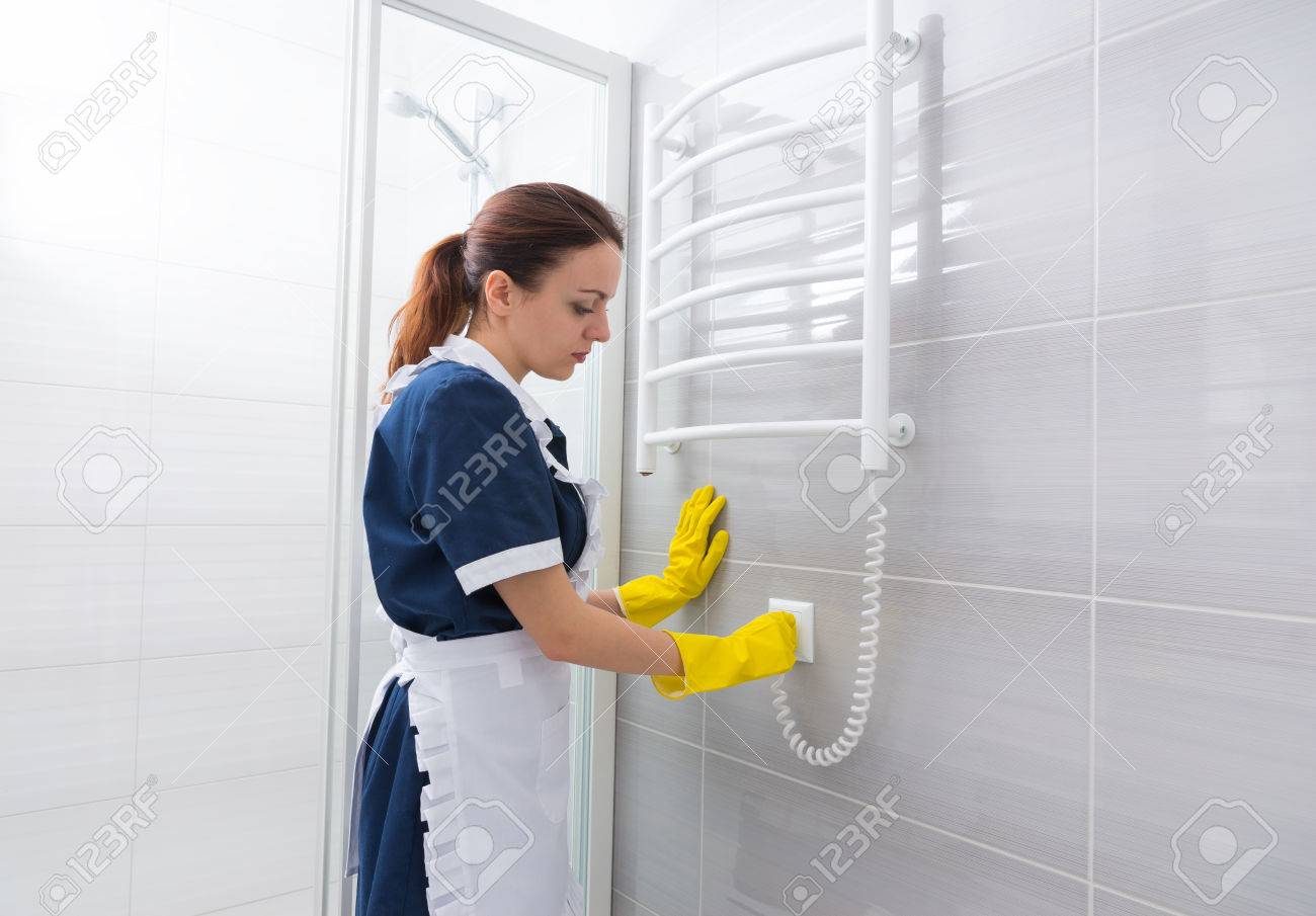 female hotel housekeeper plugging cord for heated towel rack stock hotel housekeeper