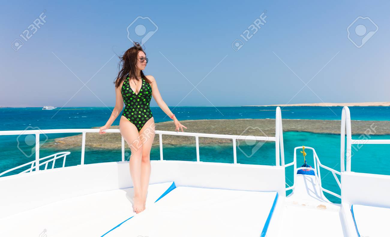 晴れた夏の日 風が髪を開発 背景に美しい海でヨットのデッキに黒緑水着立っている若い女性 の写真素材 画像素材 Image