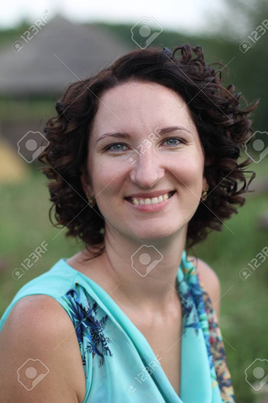 Portrait Of A Smiling Young Woman With Dark Curly Short Hair