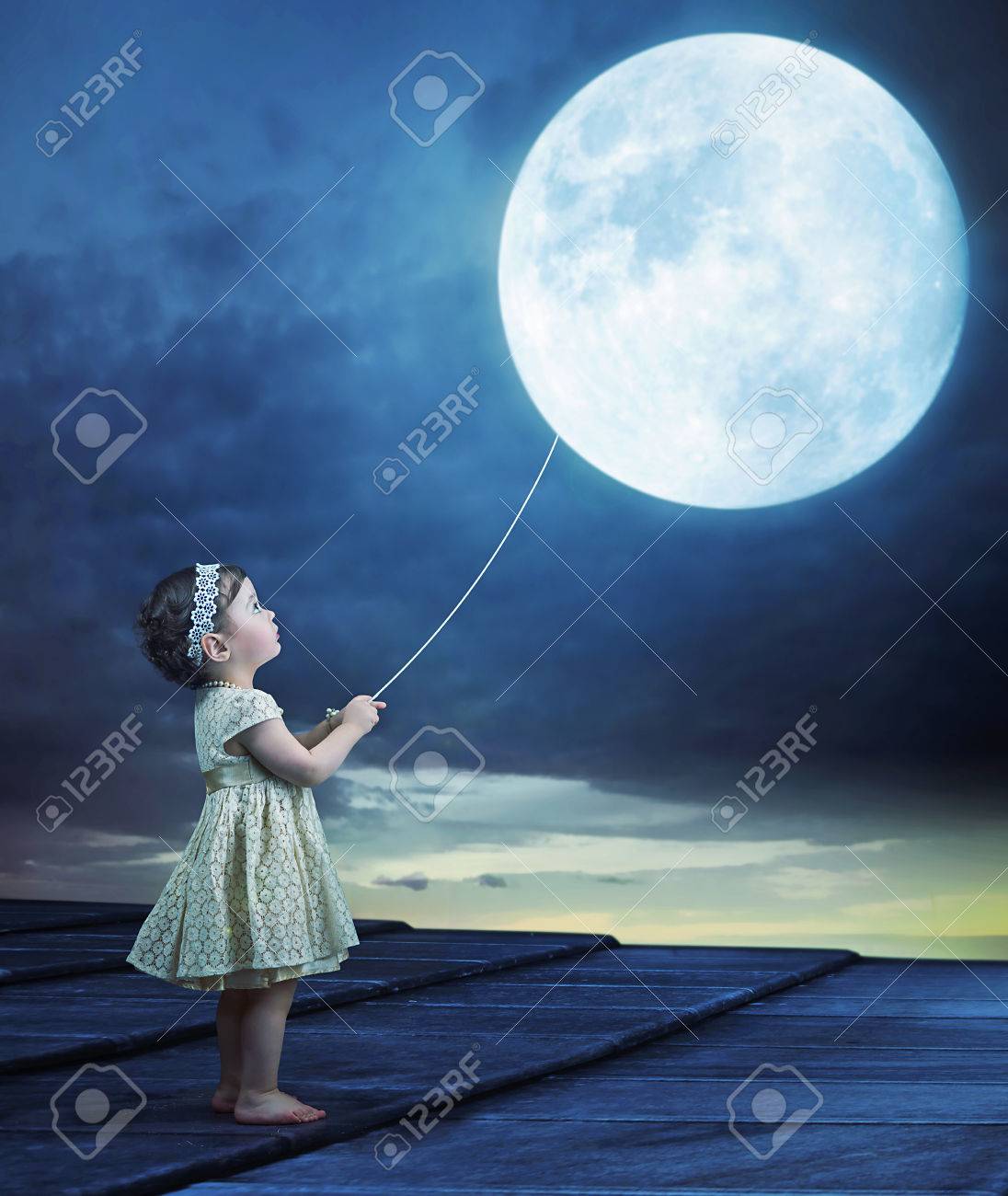 conceptual image of a cute baby holding a moon balloon stock photo
