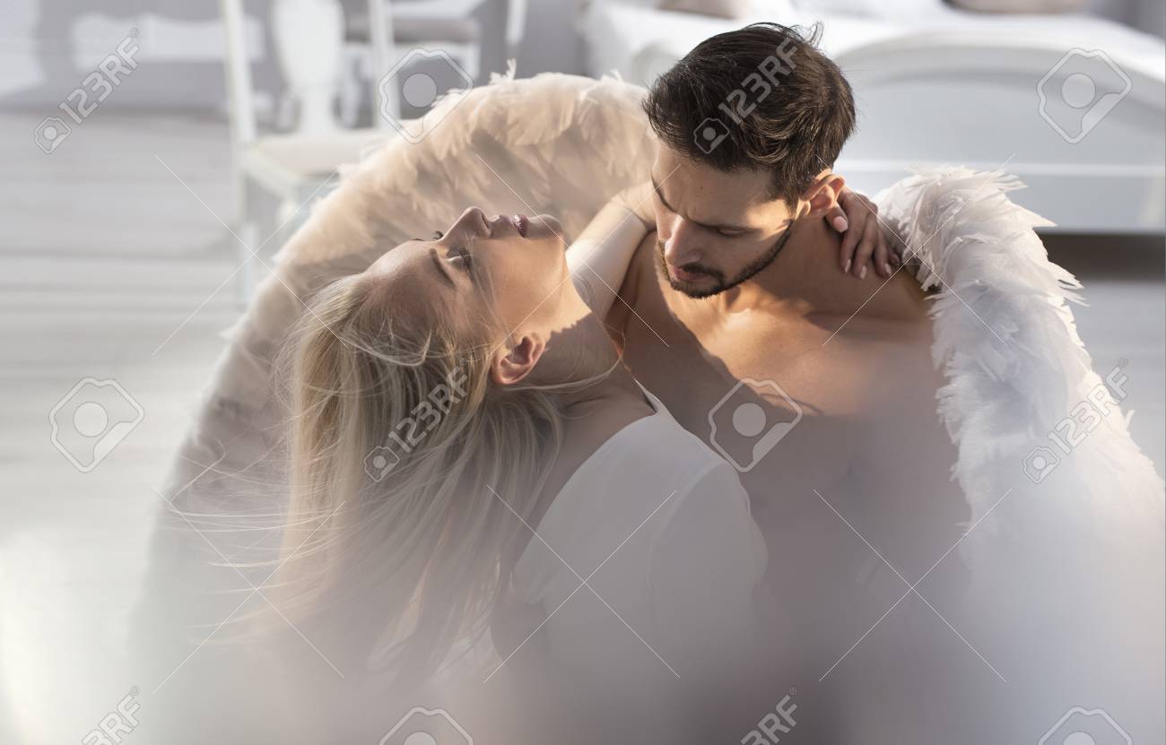 Conceptual portrait of an archangel embracing a beautiful, blond woman - 117970491 Conceptual portrait of an archangel embracing a beautiful, blond woman - 117970491