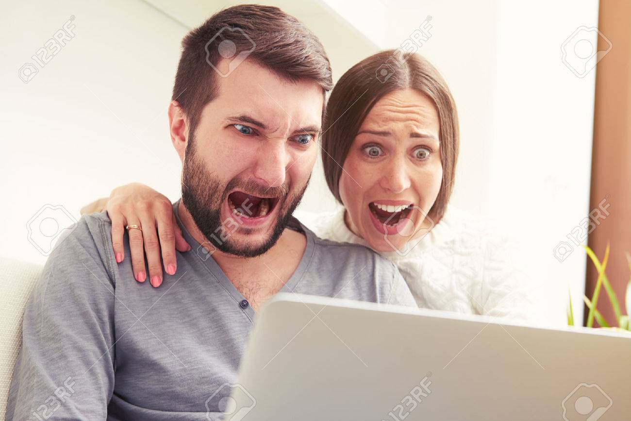 indoor photo of amazed screaming couple looking at laptop - 40300556 indoor photo of amazed screaming couple looking at laptop - 40300556