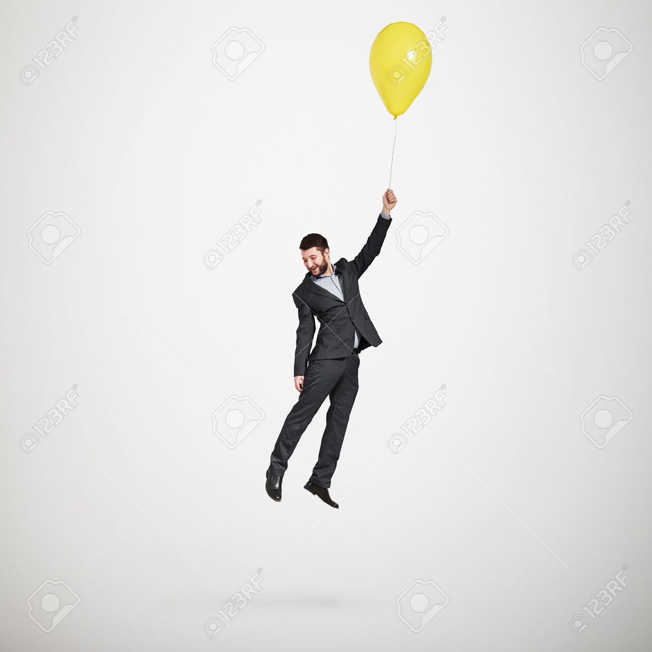 laughing man flying with yellow balloon and looking down over light grey background - 40928687 laughing man flying with yellow balloon and looking down over light grey background - 40928687