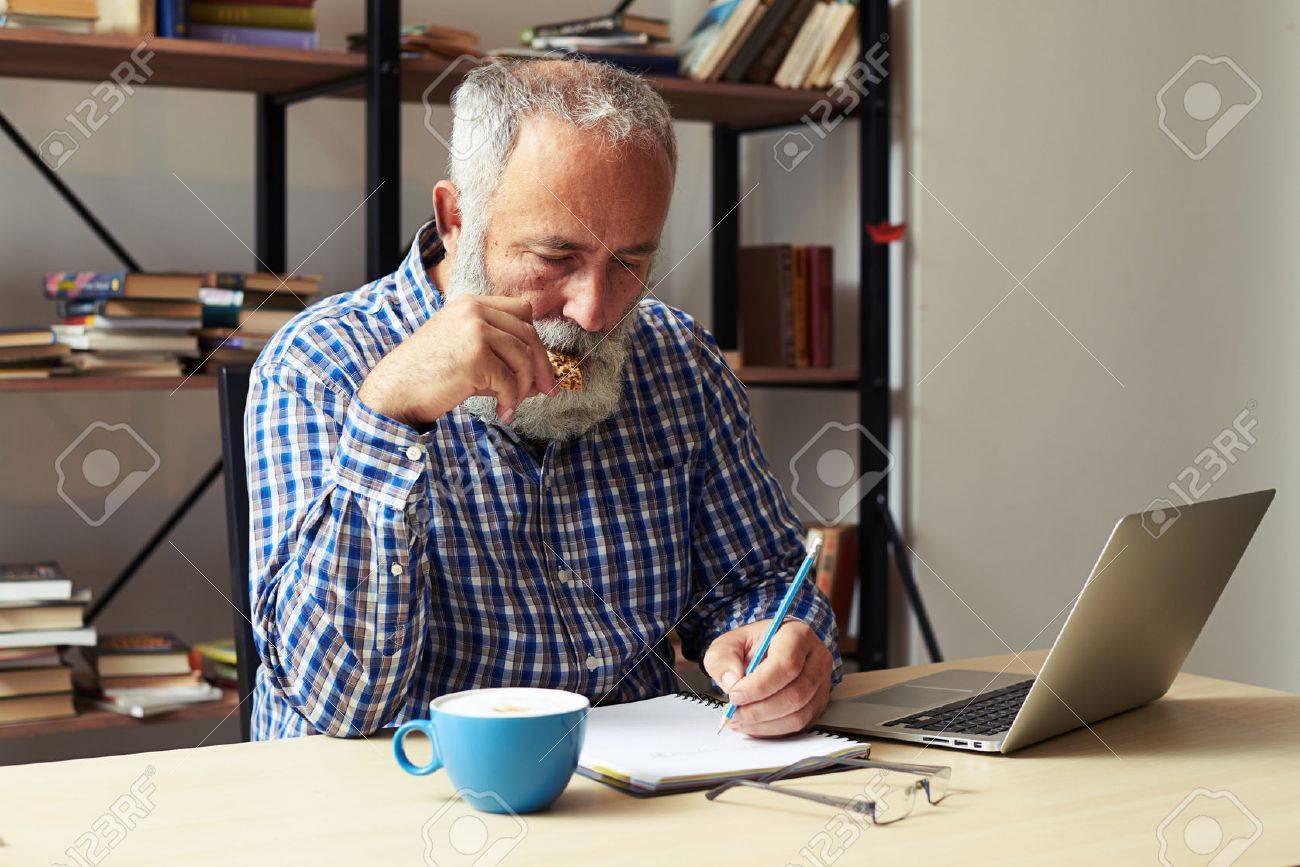 senior writer eating cookies and working in his room - 47778806 senior writer eating cookies and working in his room - 47778806