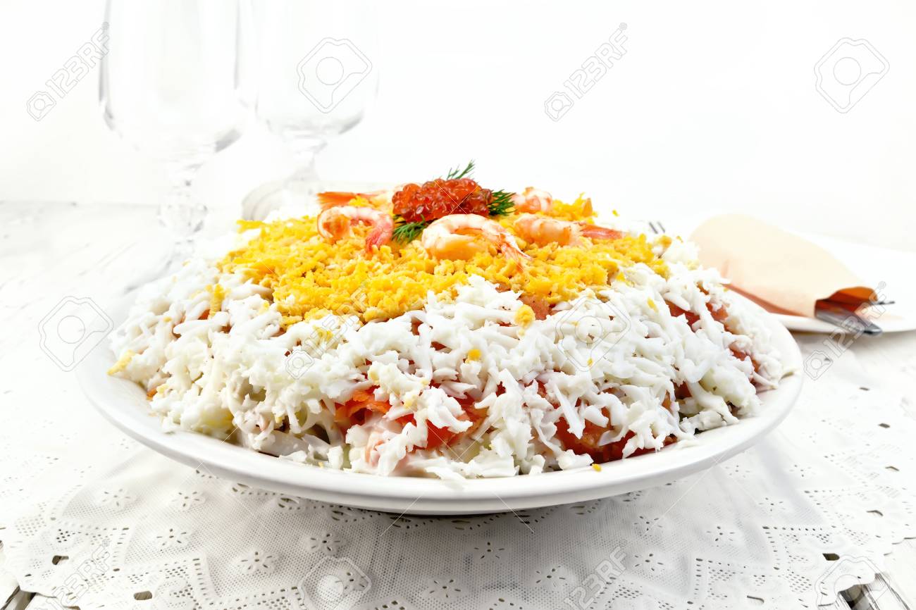 サーモン イカ エビ アボカド ご飯と背景の光の木の板にナプキン プレートで卵の層状サラダ の写真素材 画像素材 Image