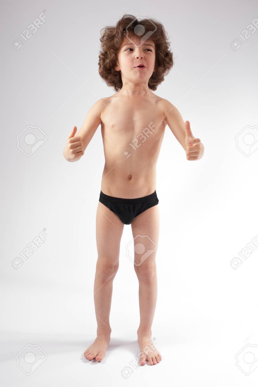 少年 パンツ ショート パンツで裸の縮れ毛の少年は、カメラと「非常に良い」ジェスチャーを示すに話します。灰色の背景。の写真素材・画像素材 Image 82564597