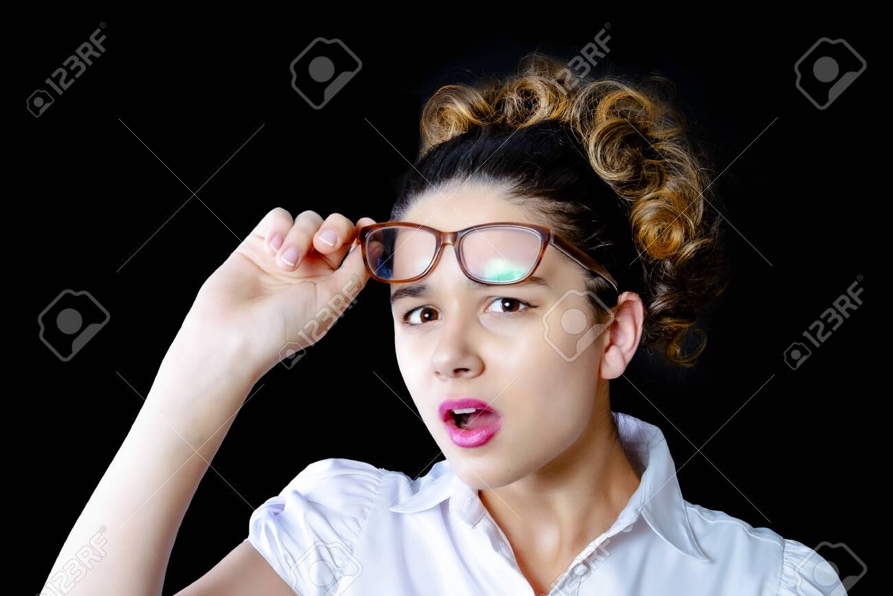 Surprised young female model with dark hair, wears glasses and a white blouse, looks with horror at the camera, notices something unexpected, hears bad news, is isolated from the black wall - 138967531 Surprised young female model with dark hair, wears glasses and a white blouse, looks with horror at the camera, notices something unexpected, hears bad news, is isolated from the black wall - 138967531