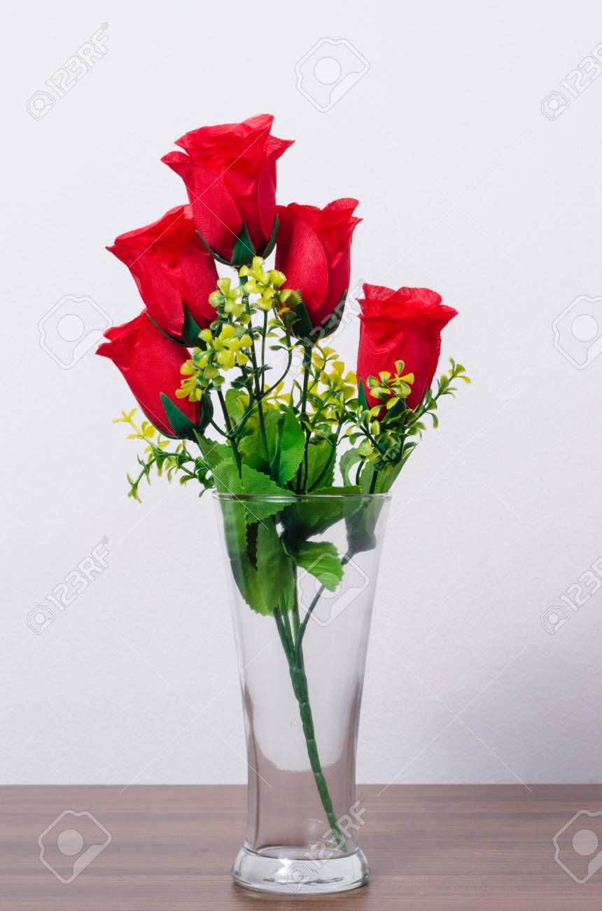 Red Artificial Rose In Glass Vase On Wooden Table Isolated On