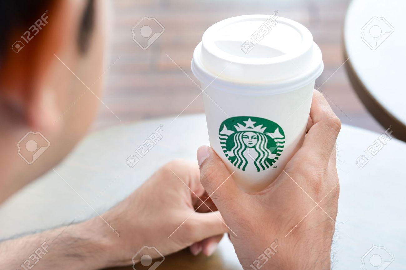 ブランドのロゴのスターバックスのコーヒー カップを保持している男 スターバックスのブランドは 米国から世界中の喫茶店チェーンです の写真素材 画像素材 Image