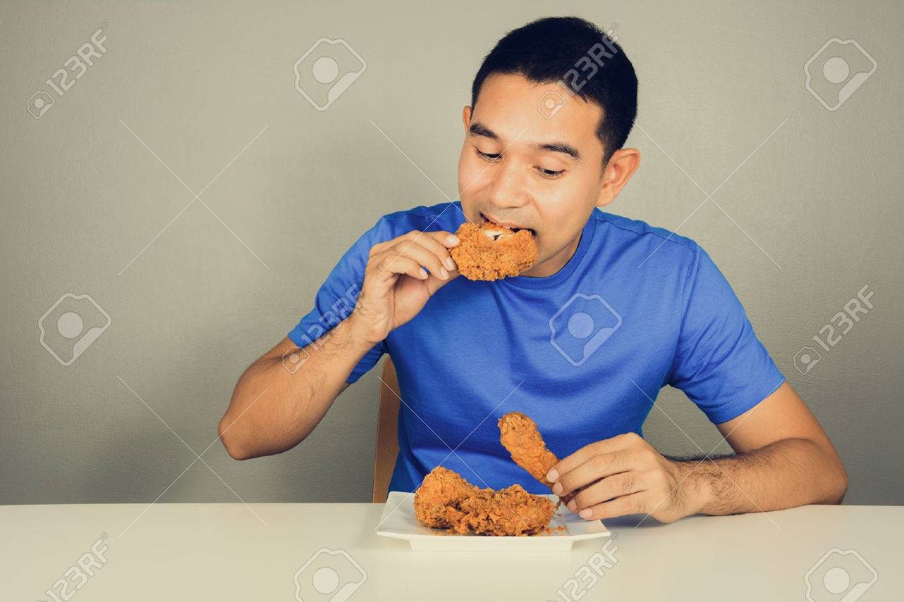 テーブル ビンテージ トーンでフライド チキンを食べる若い男 の写真素材 画像素材 Image