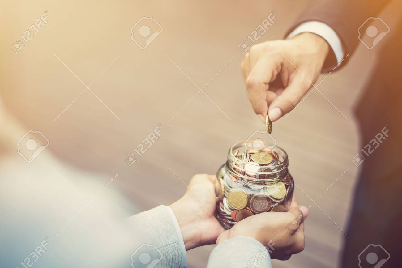 Businessman hand putting money (coin) in the glass jar held by a woman, vintage tone effect - 81597669 Businessman hand putting money (coin) in the glass jar held by a woman, vintage tone effect - 81597669