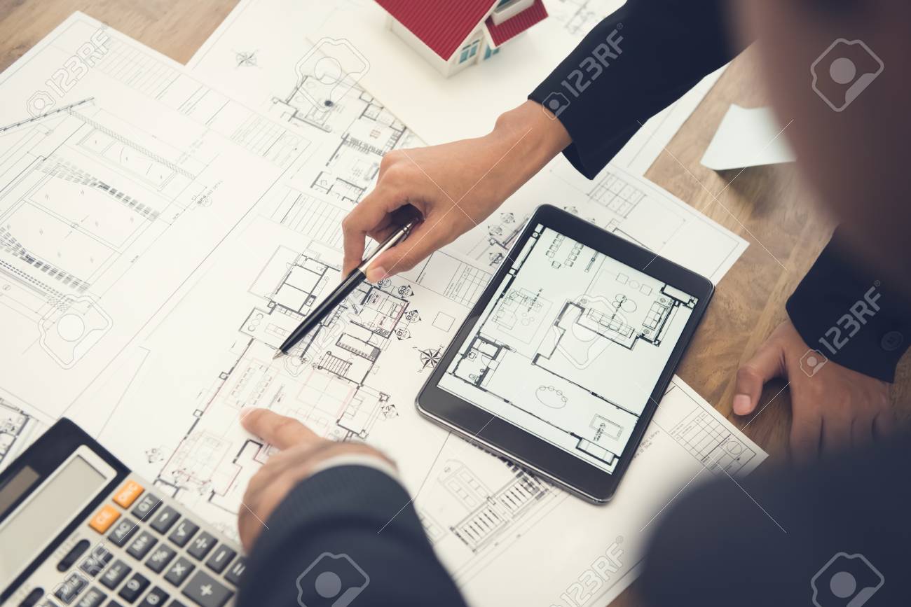 Architects or interior designers discussing floor plan blueprints on the table - 89965883 Architects or interior designers discussing floor plan blueprints on the table - 89965883