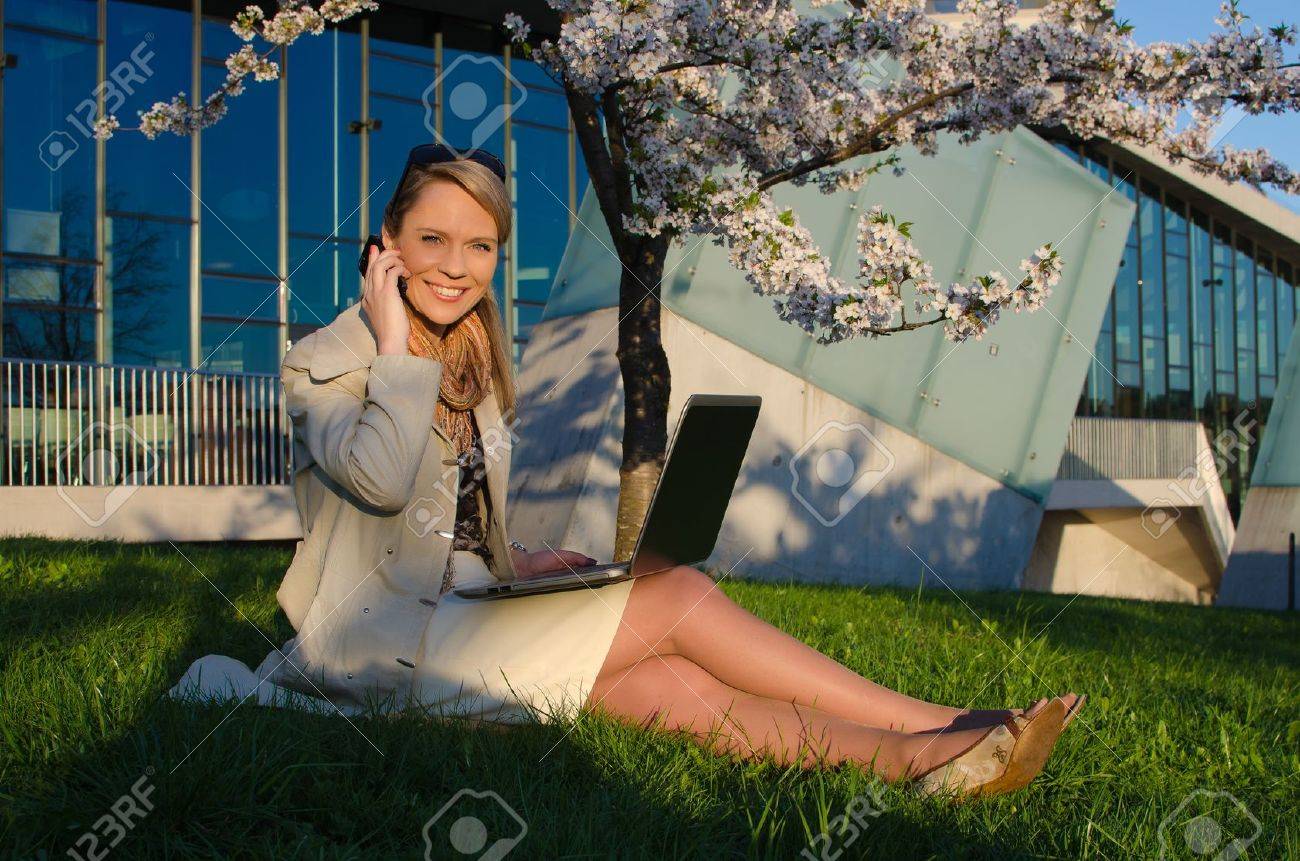 Young pretty woman with laptop talking mobile phone - 21735141 Young pretty woman with laptop talking mobile phone - 21735141