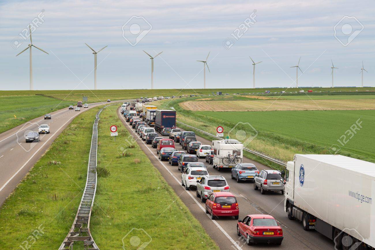 LELYSTAD - AUGUST 17: Traffic moves slowly along a busy highway along a dike and wind turbines on August 17, 2012 in Lelystad, The Netherlands - 17393180 LELYSTAD - AUGUST 17: Traffic moves slowly along a busy highway along a dike and wind turbines on August 17, 2012 in Lelystad, The Netherlands - 17393180