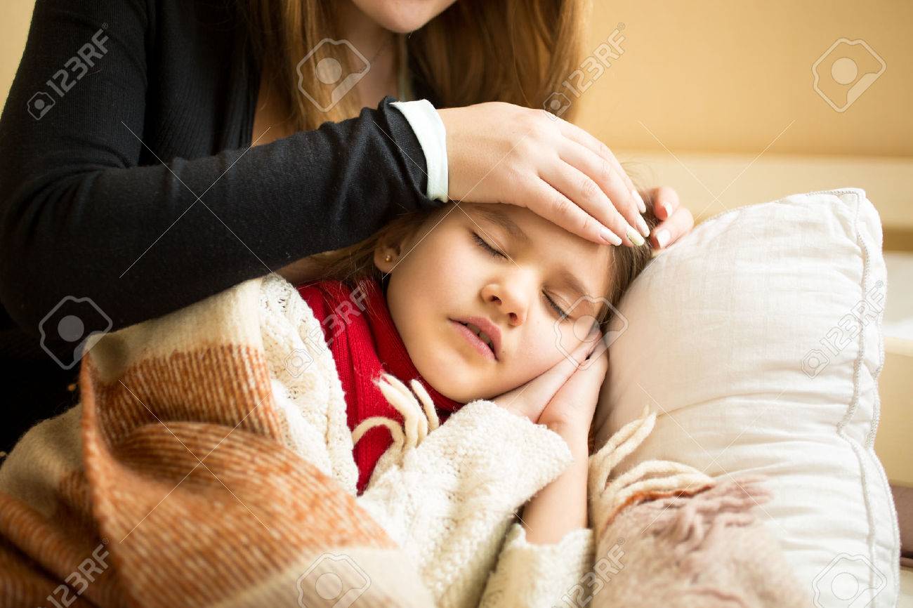 Closeup photo of caring mother holding head on sick daughter forehead - 41681672 Closeup photo of caring mother holding head on sick daughter forehead - 41681672