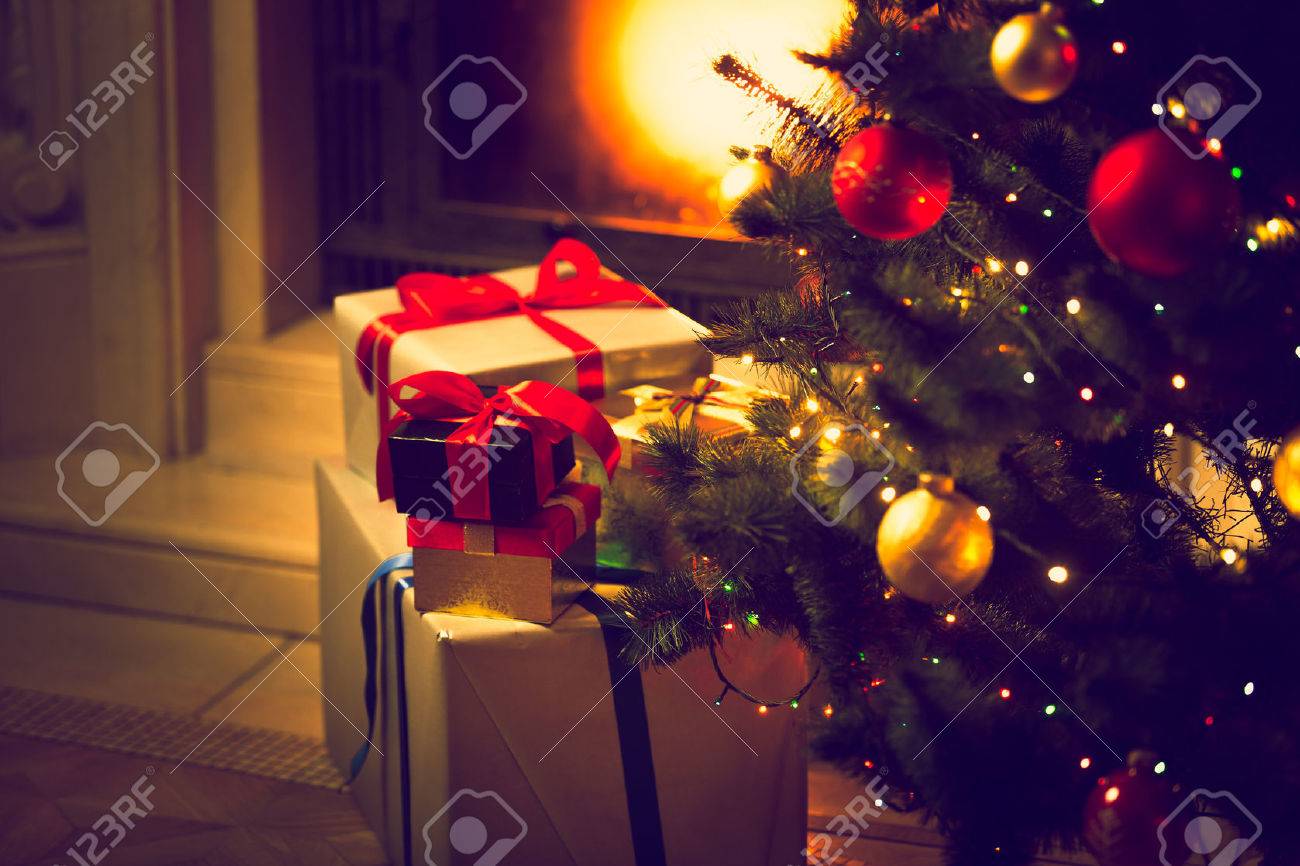 Toned photo of decorated Christmas tree and gift boxes against burning fireplace - 45224436 Toned photo of decorated Christmas tree and gift boxes against burning fireplace - 45224436