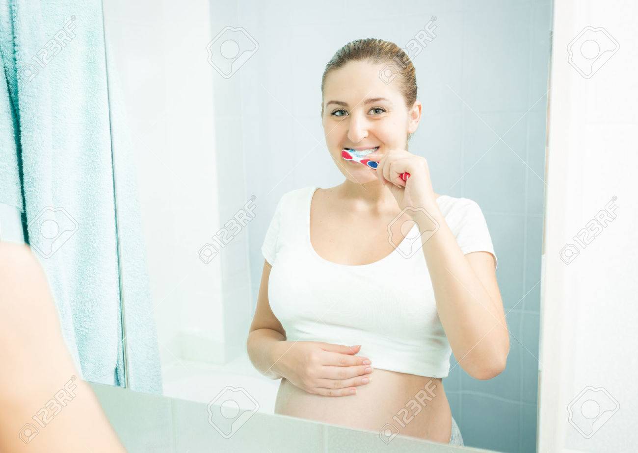 Portrait of young pregnant woman brushing teeth at bathroom - 46388751 Portrait of young pregnant woman brushing teeth at bathroom - 46388751