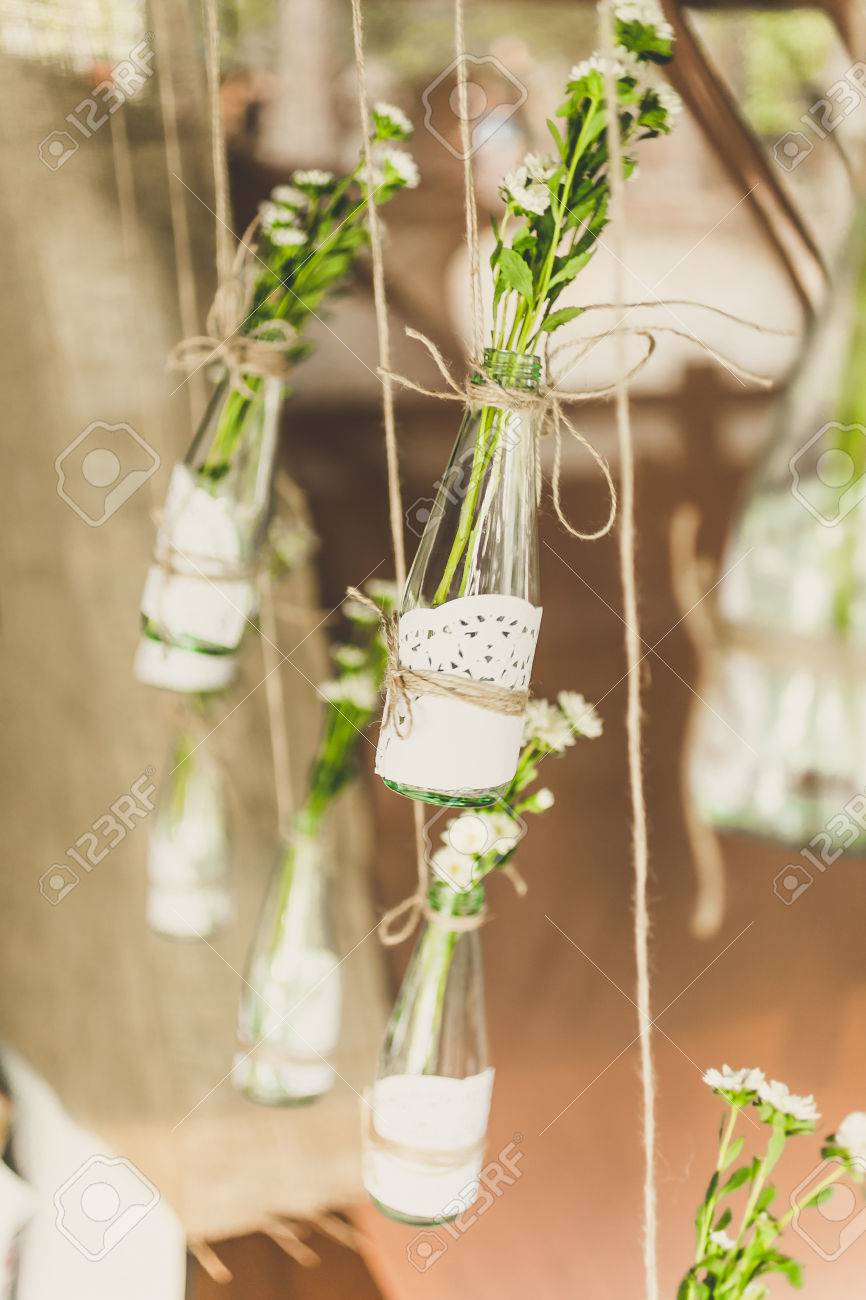 Closeup toned photo of decorated bottles with flowers hanging on twine - 46546378 Closeup toned photo of decorated bottles with flowers hanging on twine - 46546378