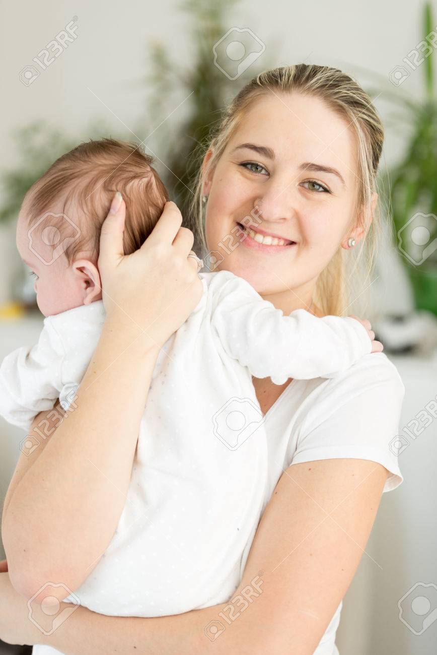 彼女の 3ヶ月の赤ちゃんを抱きしめる母親を美しい笑顔の肖像画 の写真素材 画像素材 Image