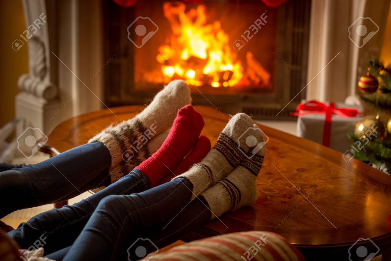 Male and female feet in woolen socks warming at burning fireplace - 81283285 Male and female feet in woolen socks warming at burning fireplace - 81283285