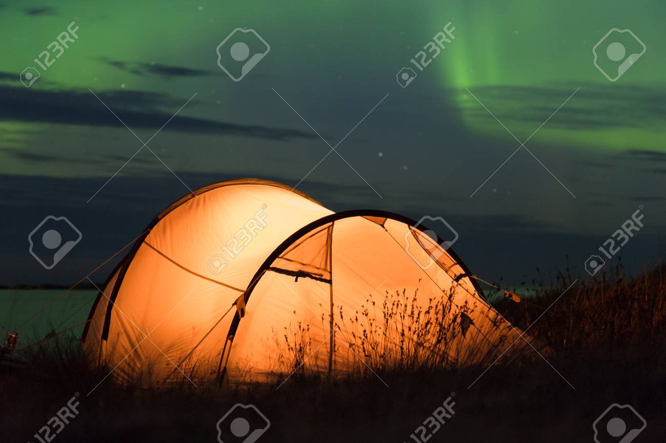 Northern lights dancing over an iluminated tent at the Atlantic coast in Norway - 81938553 Northern lights dancing over an iluminated tent at the Atlantic coast in Norway - 81938553