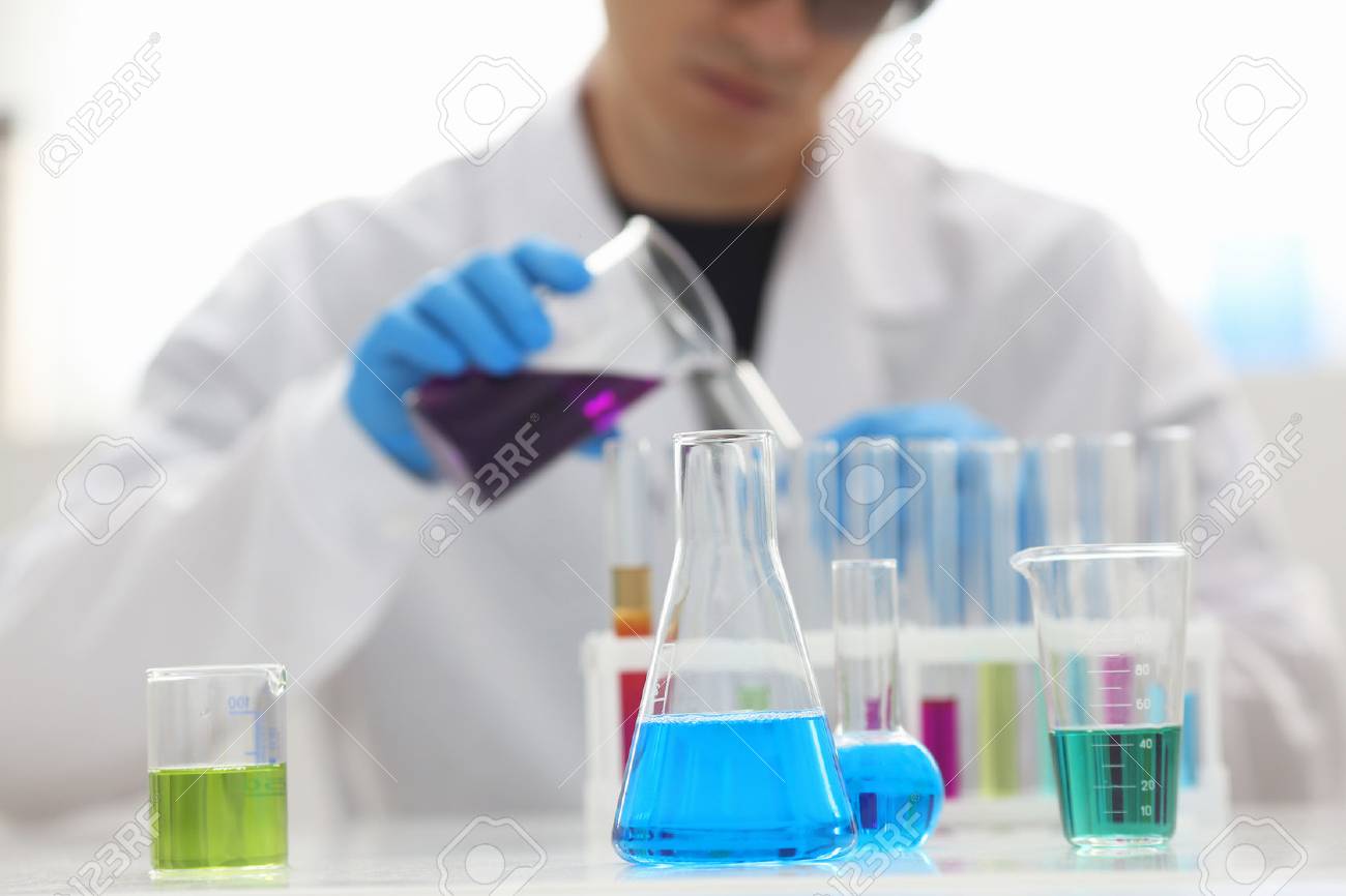 A male chemist holds test tube of glass in his hand overflows a liquid solution of potassium permanganate conducts an analysis reaction takes various versions of reagents using chemical manufacturing - 87599955 A male chemist holds test tube of glass in his hand overflows a liquid solution of potassium permanganate conducts an analysis reaction takes various versions of reagents using chemical manufacturing - 87599955