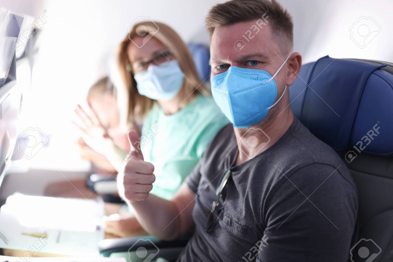 Husband and wife are flying on plane wearing medical masks. Sanitary standards of flight during epidemic of coronavirus infection concept. - 155437737 Husband and wife are flying on plane wearing medical masks. Sanitary standards of flight during epidemic of coronavirus infection concept. - 155437737