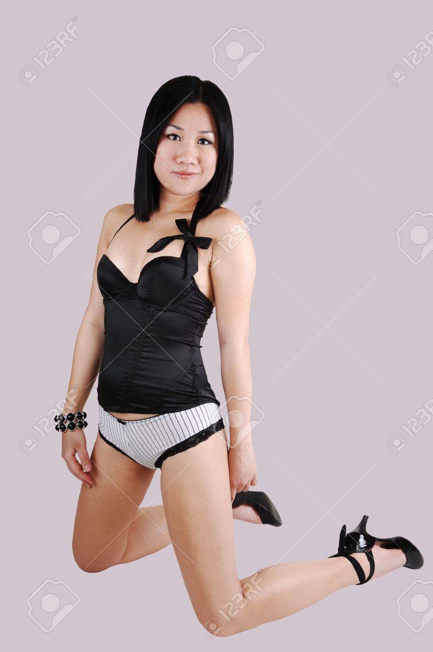 a pretty chinese woman kneeling on the floor in black and white