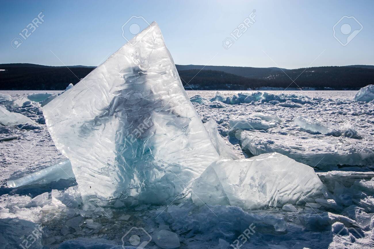 A Huge Ice Piece Frozen Into Lake Baikal, Behind Which A Man Stands. Clear  Skies, Hills Behind A Lake With Snow And Scattered Ice. Stock Photo,  Picture And Royalty Free Image. Image