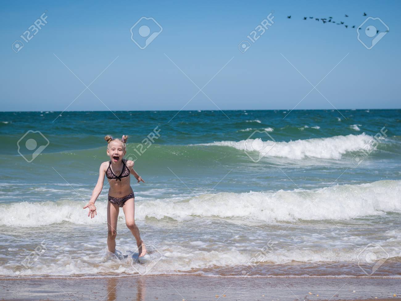 女の子は 荒れ狂う海から恐怖で逃げます 風は海に膨脹可能なマットレスを運ぶ 少女は恐怖で逃げます の写真素材 画像素材 Image