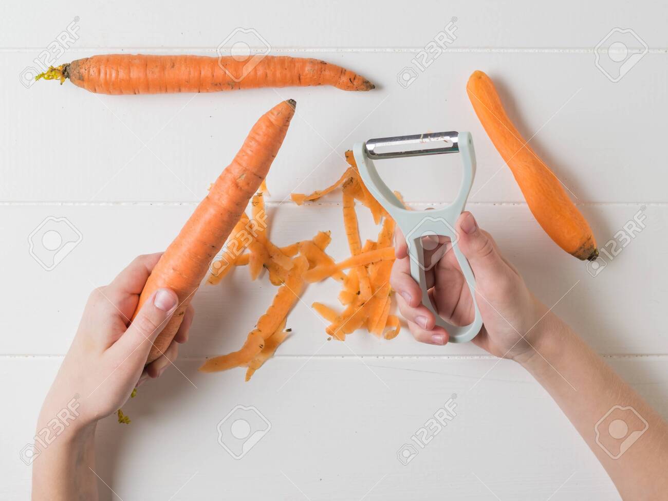 The Child Is Engaged In Cleaning Carrots With A Vegetable Peeler Stock Photo Picture And Royalty Free Image Image 143578442